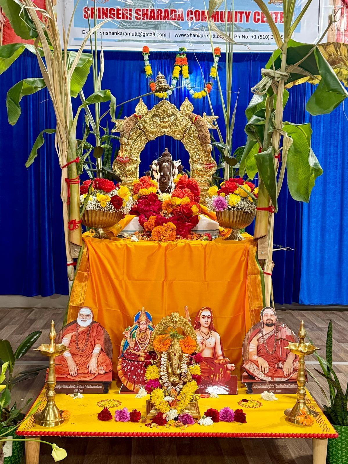 Puja altar decorated with banana plants, flowers and portraits of the Acharyas