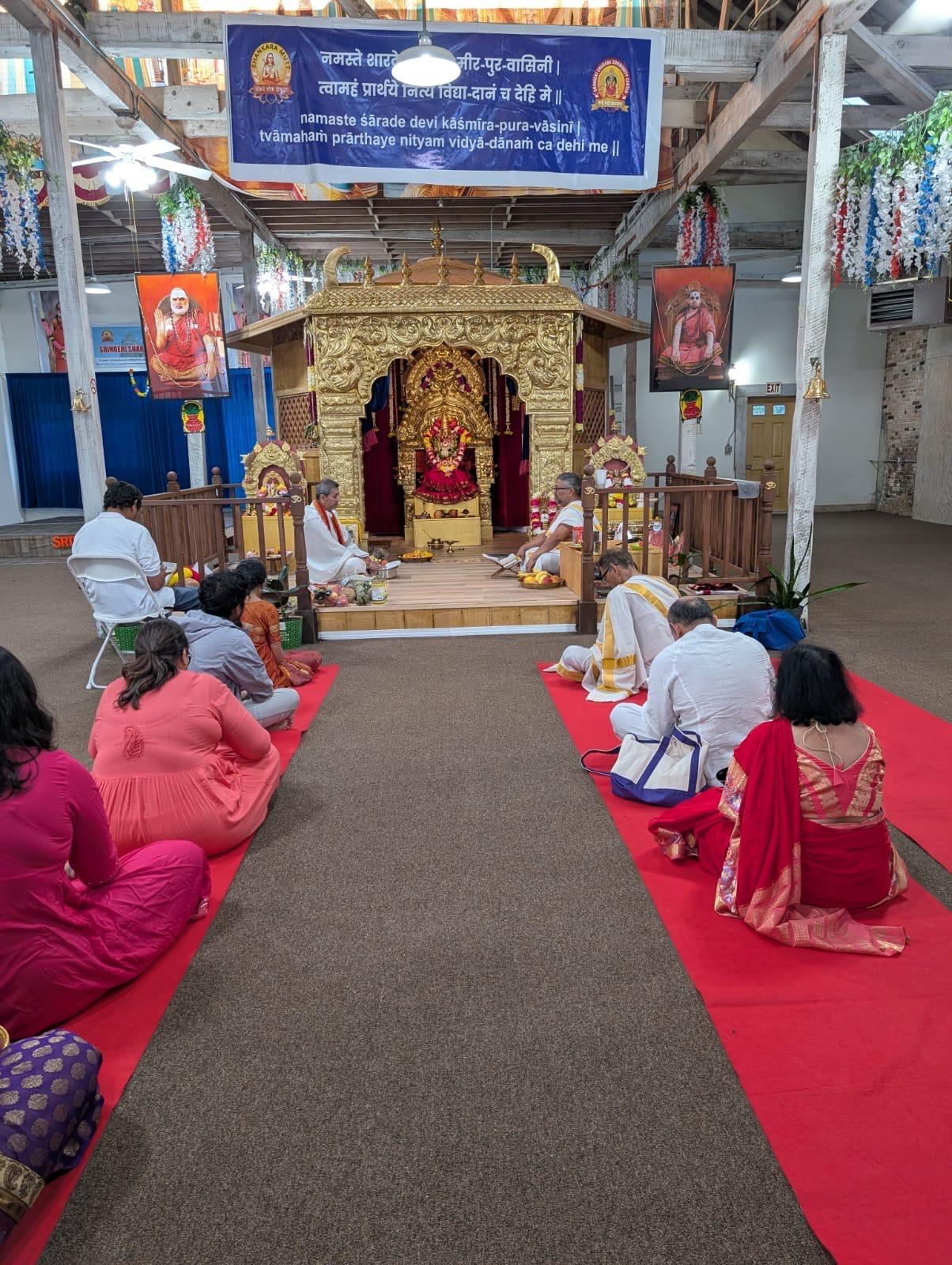Devotees seated in the prayer hall during puja
