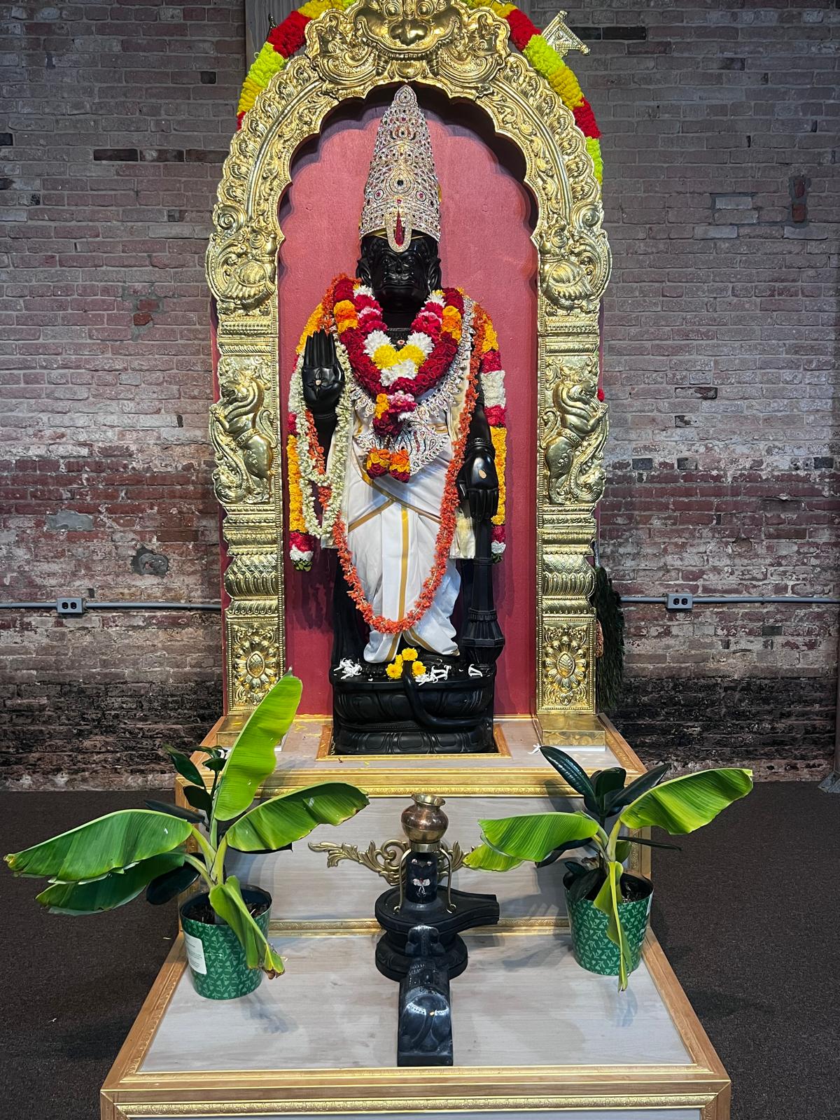 Black deity idol flanked by banana plants